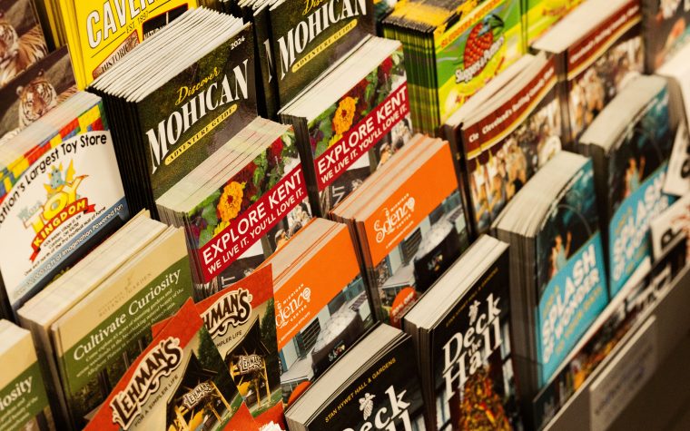 Colorful collection of travel brochures on display at a bookstore. Collection colorée de brochures de voyage exposées dans une librairie.