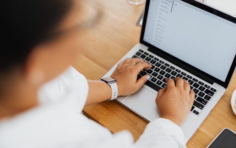 High angle shot of a person typing on a laptop, focused on hands and keyboard. Vue de haut d'une personne tapant sur un ordinateur portable, focus sur les mains et le clavier.