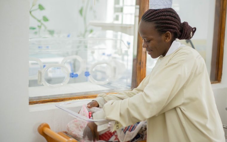 A nurse tending to a newborn in a hospital nursery, showing care and compassion. Une infirmière s'occupant d'un nouveau-né dans une pouponnière d'hôpital, montrant soin et compassion.