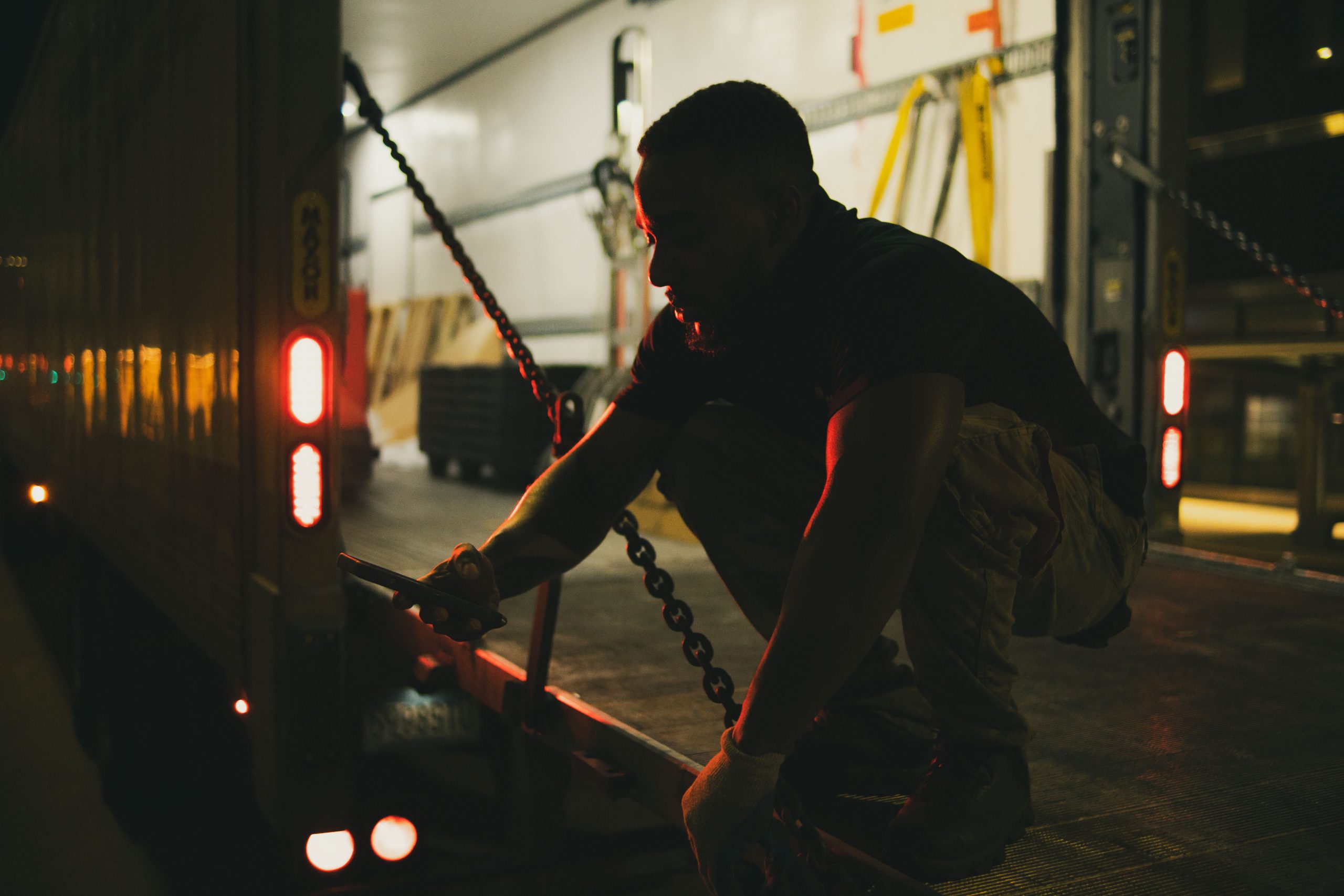 Manutentionnaire fixant chaînes camion nuit