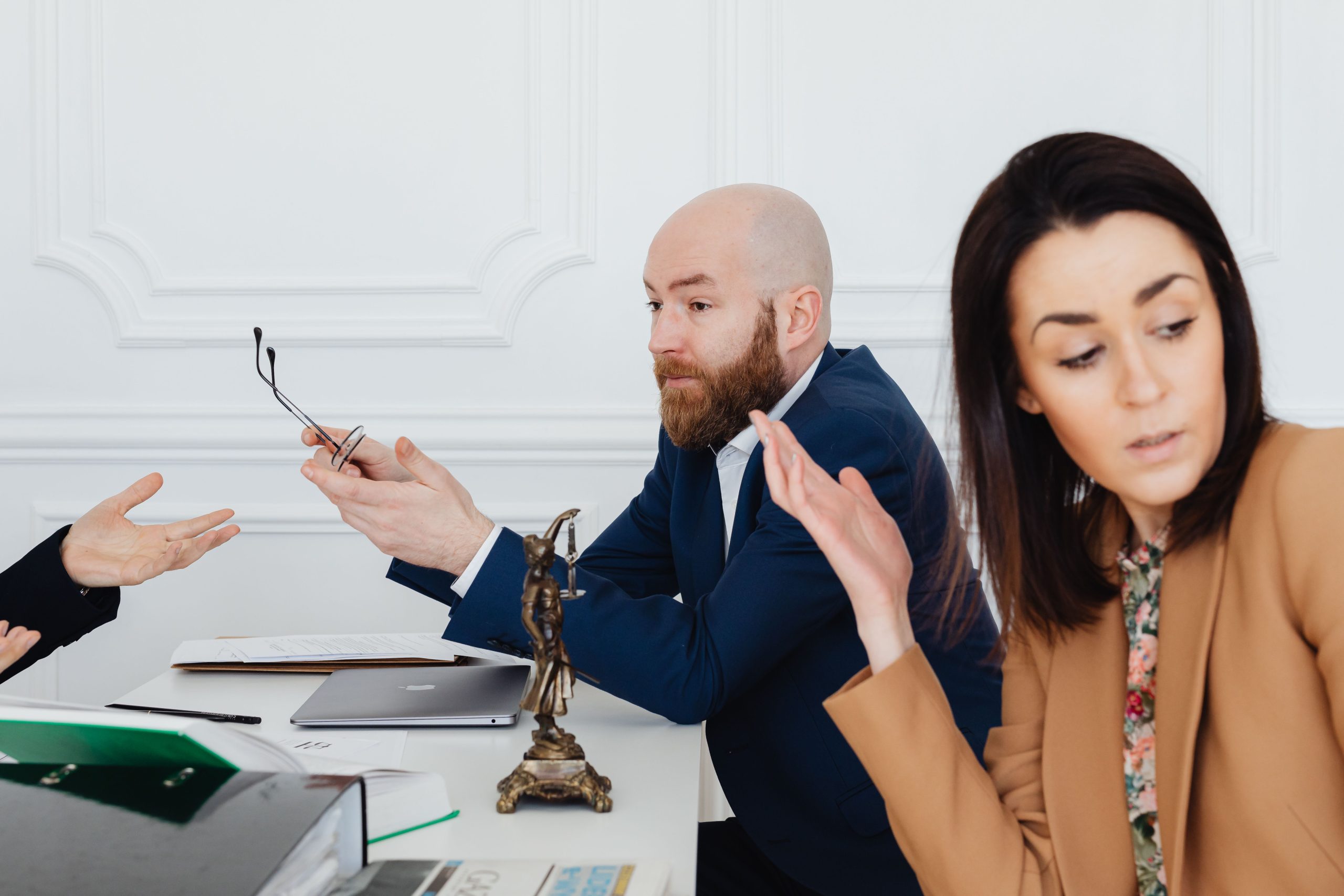 Trois adultes en discussion animée avec documents légaux