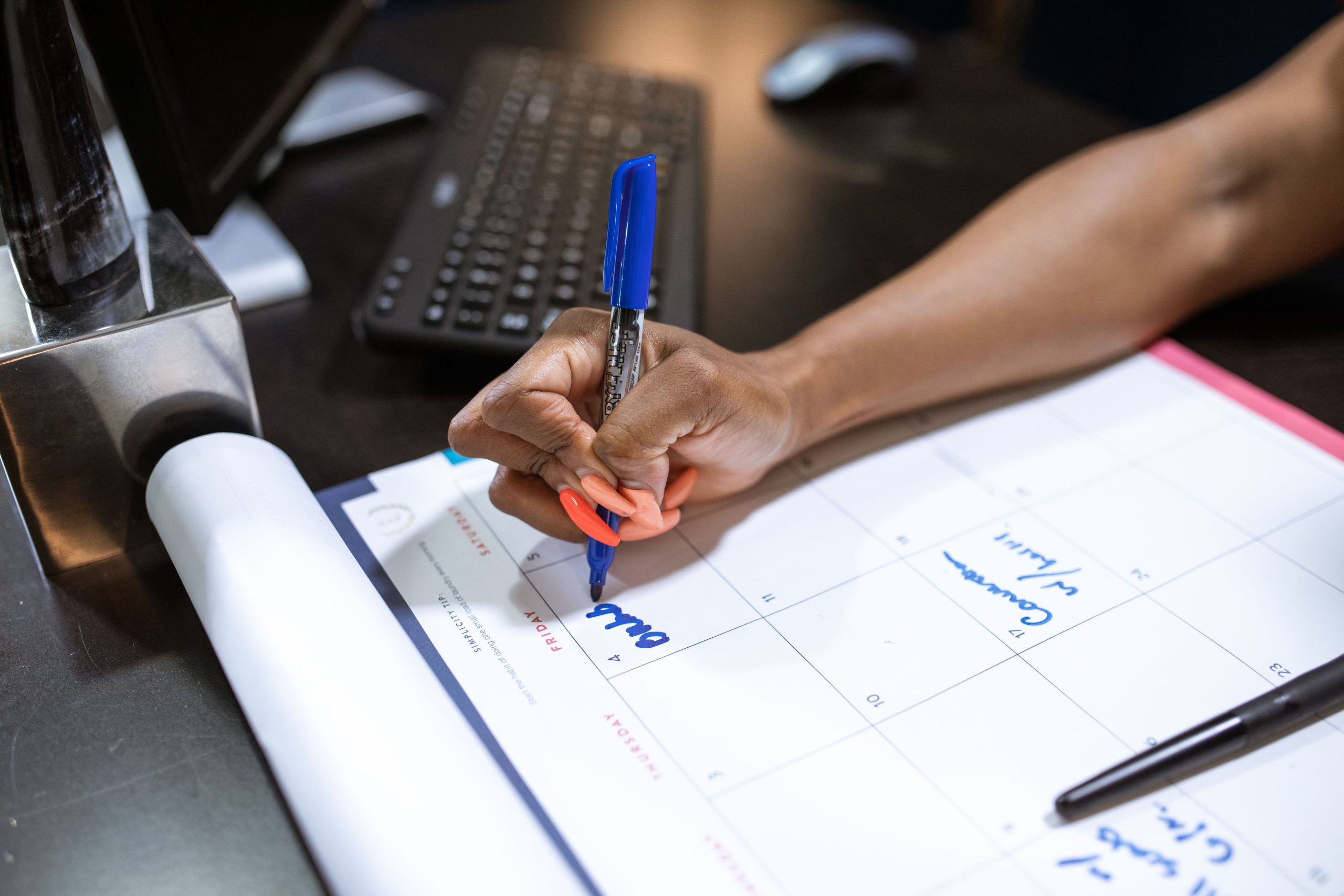 Main écrivant notes sur calendrier bleu