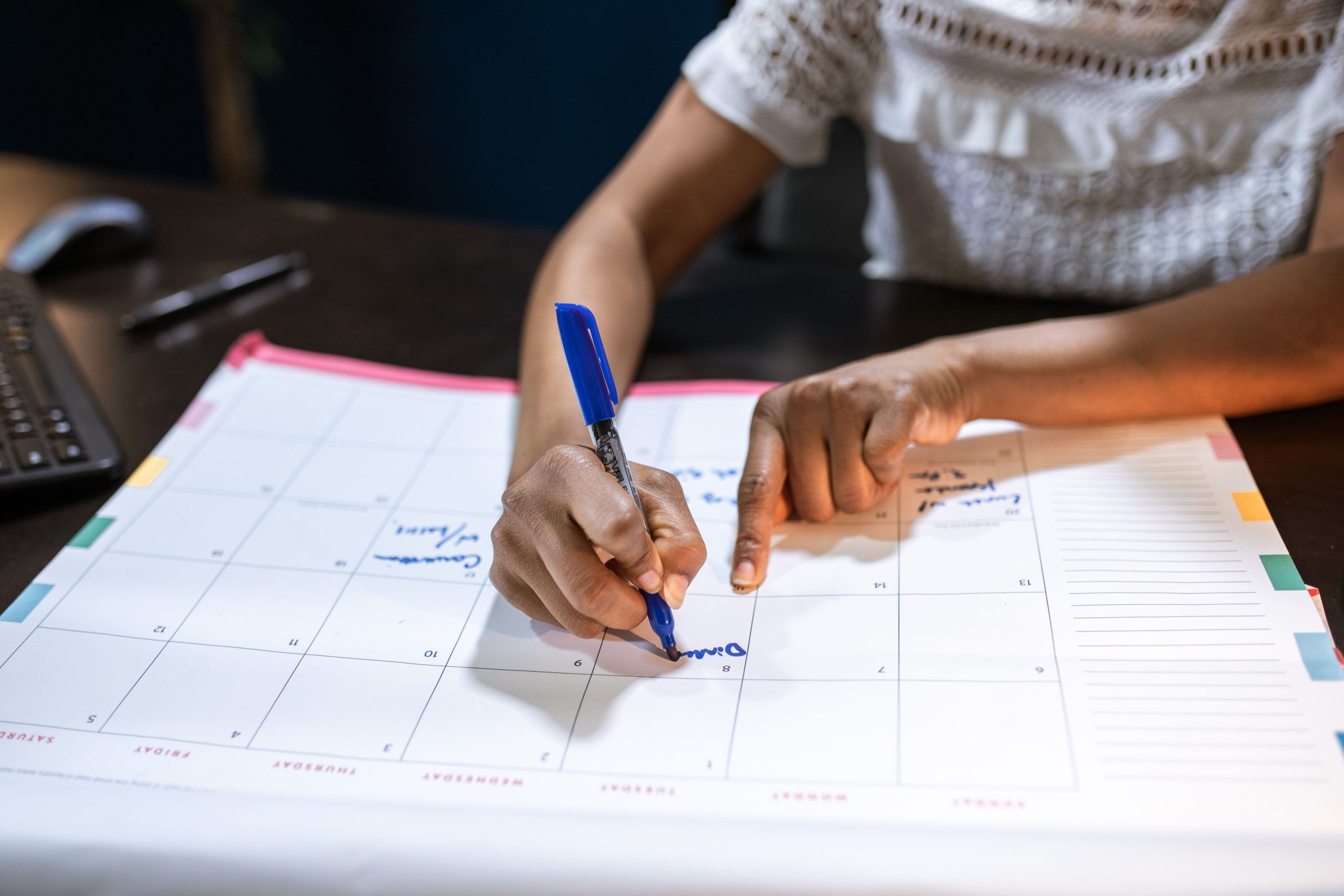Femme marquant dates importantes sur calendrier bureau