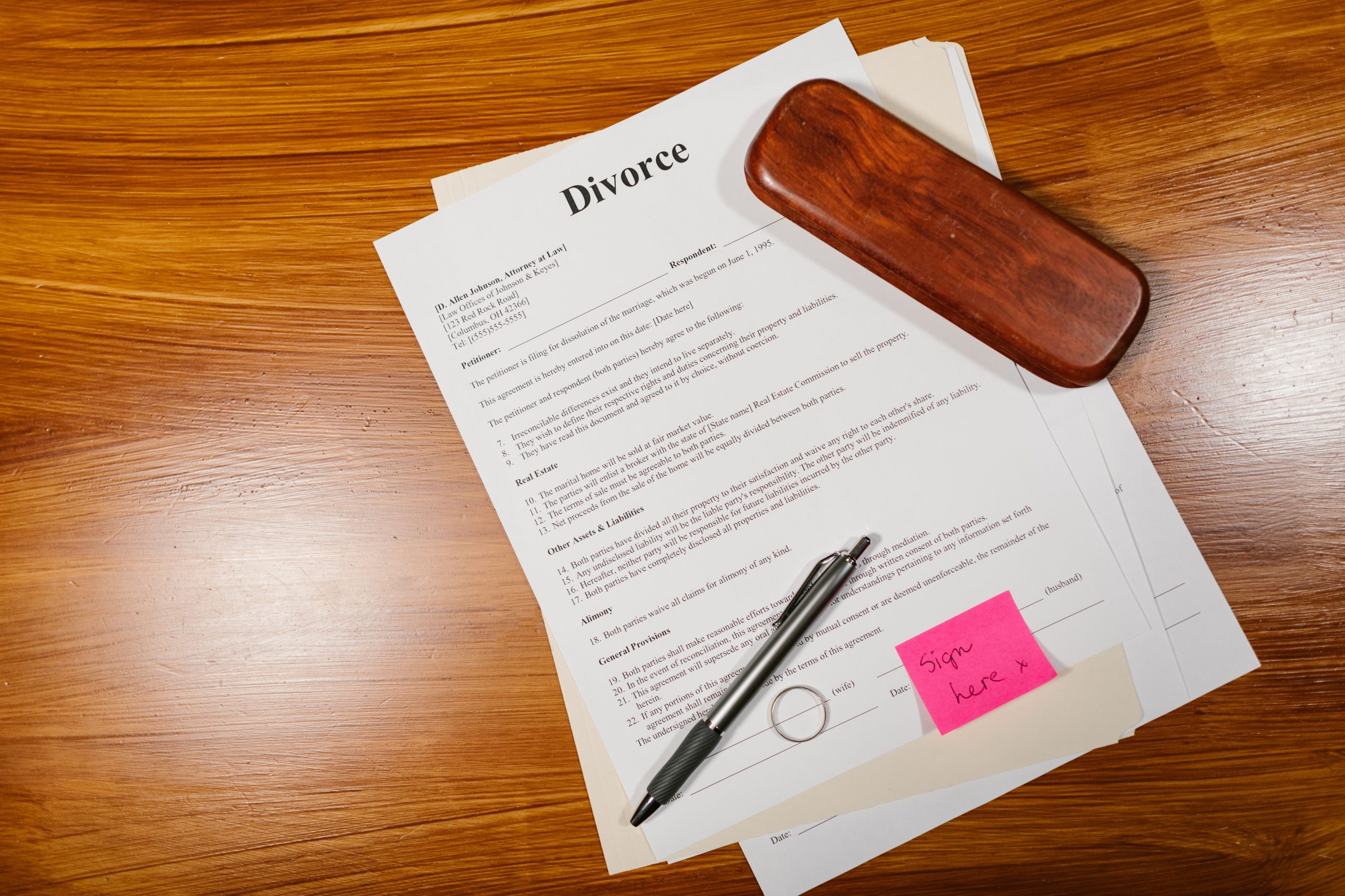Papiers divorce avec stylo et alliance sur table