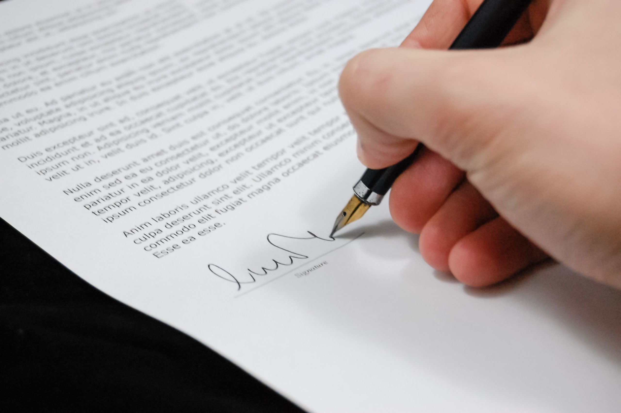 Main signant un document legal avec stylo plume