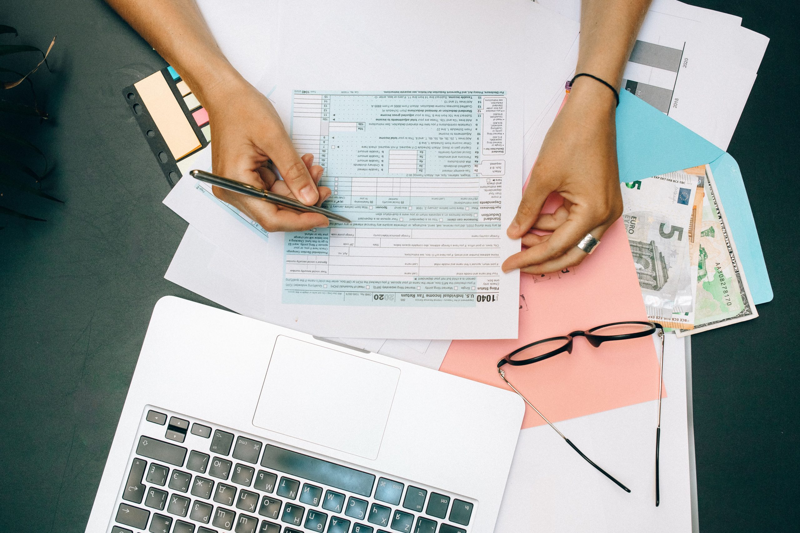 Mains remplissant des documents fiscaux avec ordinateur portable