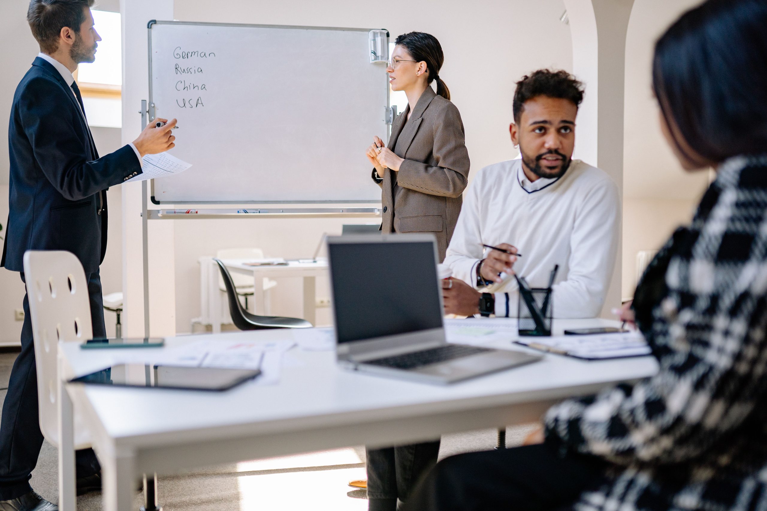 Équipe diversifiée collaborant avec ordinateurs et tableau blanc