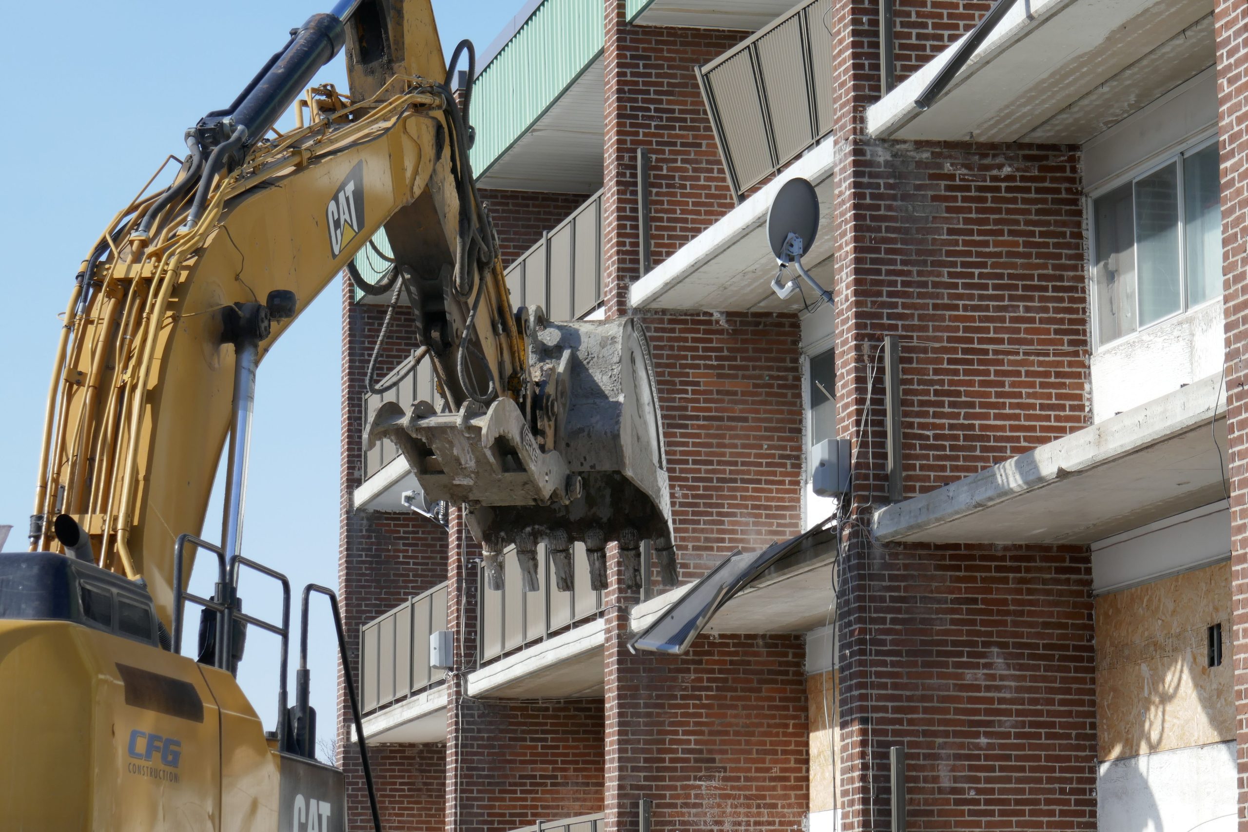 Excavatrice démolissant immeuble résidentiel urbain
