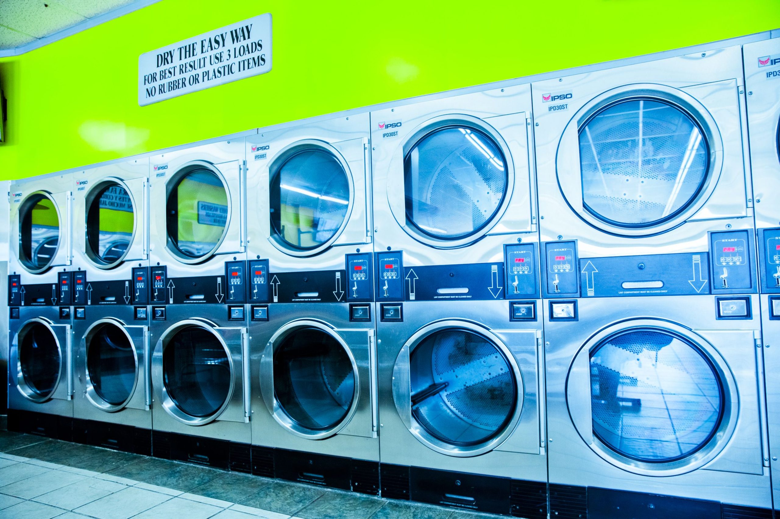 Laverie moderne avec sèche linge en inox et mur vert